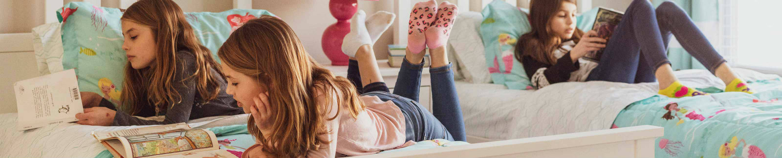 3 young sisters reading books on their beds
